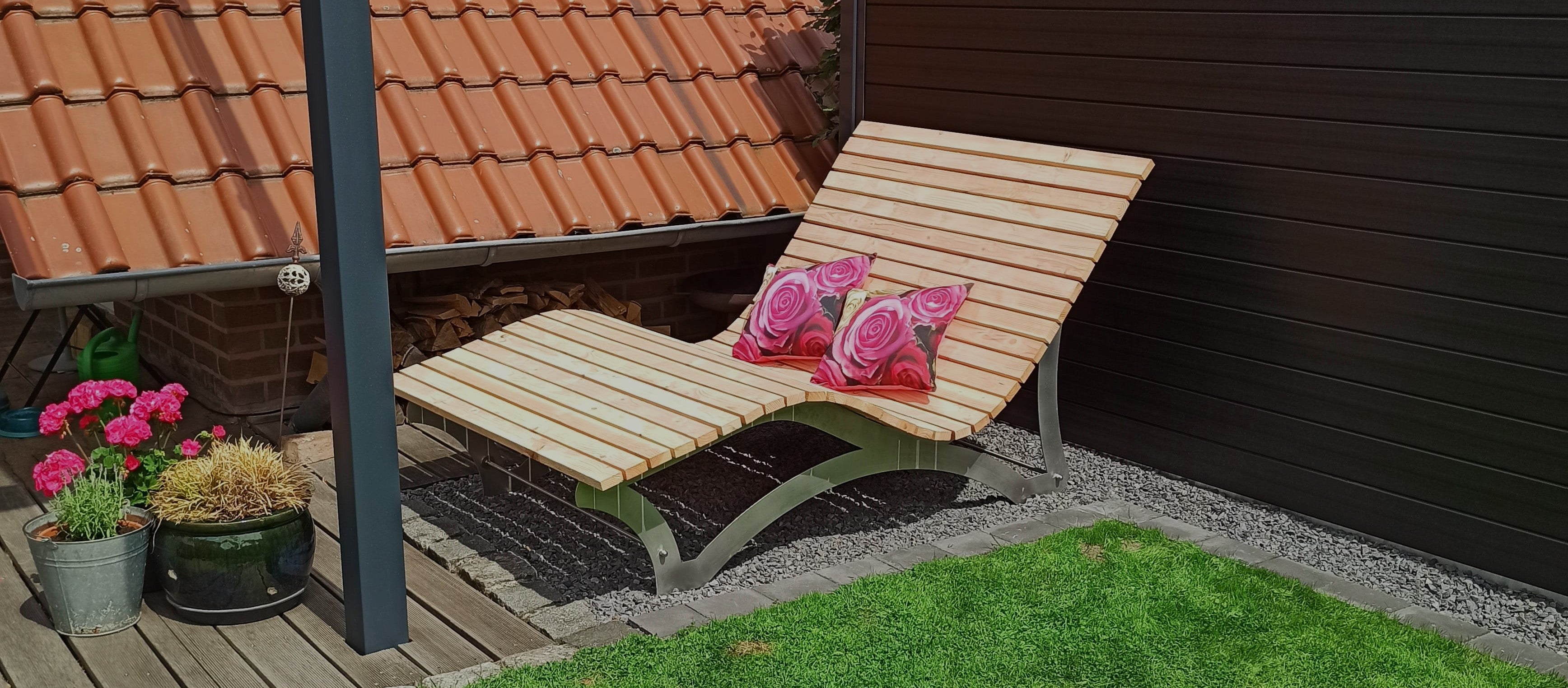 Ein Holzdeckstuhl auf dem Rasen neben einem Haus.